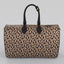 A Sahara leopard print large duffel bag with black handles and gold-tone hardware, shown against a neutral light gray background.