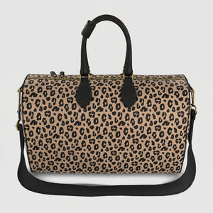 A Sahara leopard print large duffel bag with black handles, a black shoulder strap, and gold-tone hardware, shown against a light gray background.