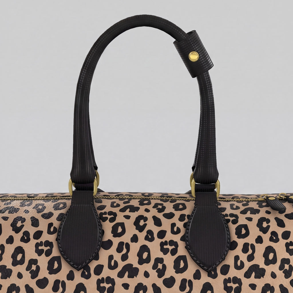 Close-up of a large Sahara leopard-print handbag with black leather handles and gold-tone hardware against a light gray background.