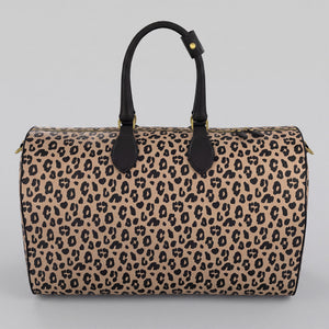 A Sahara leopard print large duffel bag with black handles and gold-tone hardware, shown against a neutral light gray background.